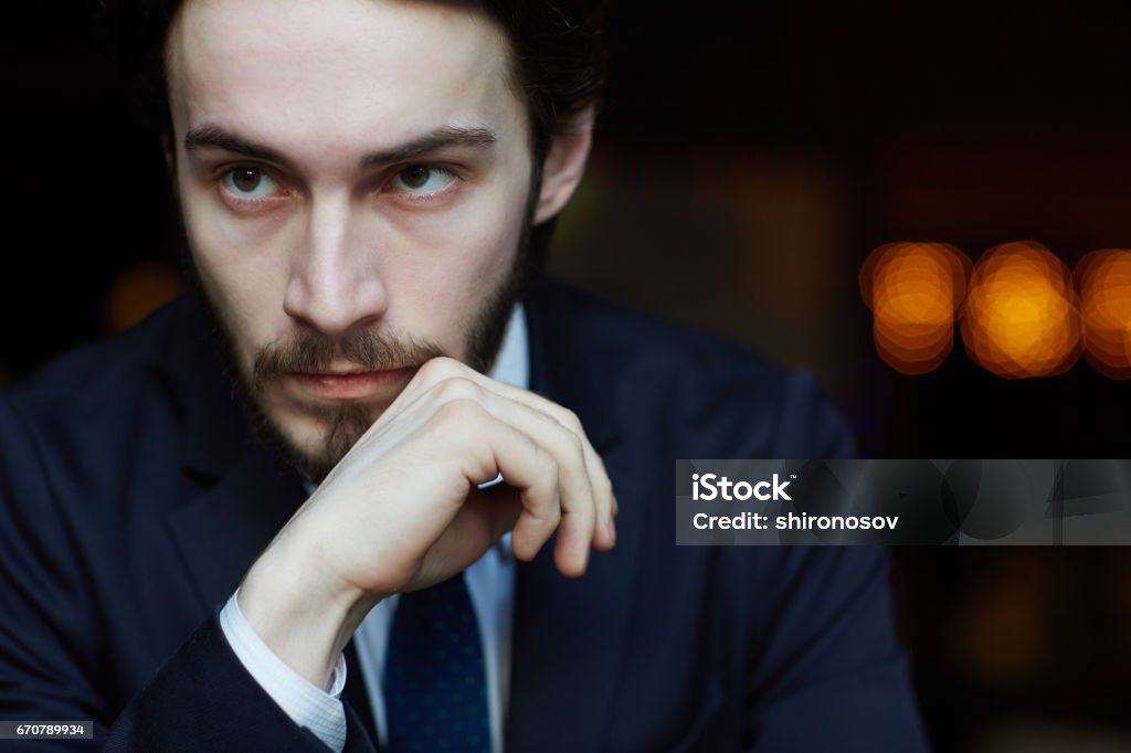 Portrait of Pensive Elegant Man Head and shoulders portrait of handsome bearded man wearing elegant business suit, deep in thought, looking away from camera Adult Stock Photo