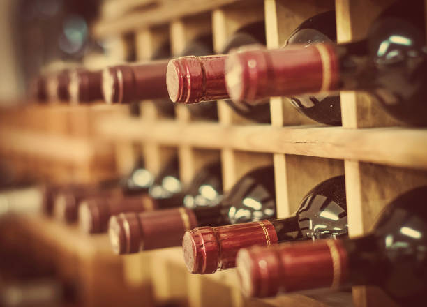 Red wine bottles stacked on wooden racks stock photo