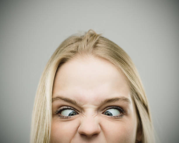 istock Crosseyed woman grimacing against gray background 670796220