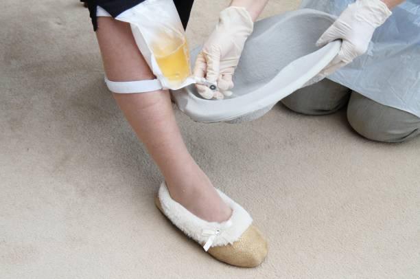 Nurse or care worker emptying urine drainage bag Nurse or care worker emptying urine drainage bag of elderly female in own home or nursing home . catheter stock pictures, royalty-free photos & images