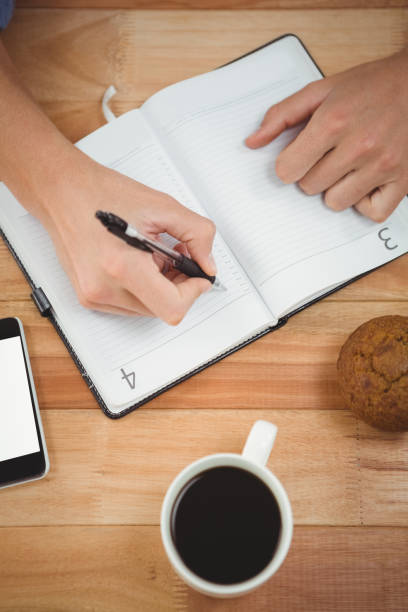 istock Man writing on diary with muffin and coffee at desk 670804948