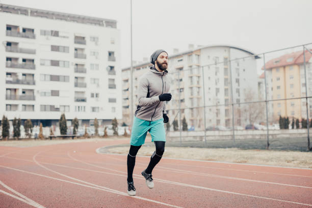 istock Handsome athlete jogging on the running track 670812266