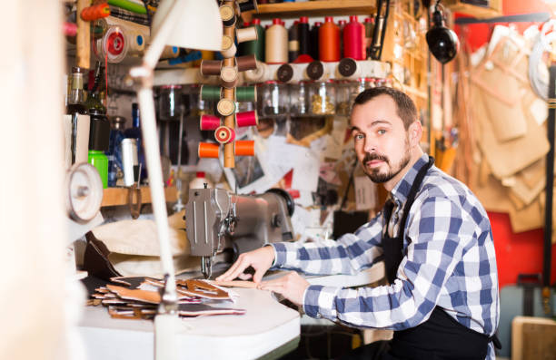 istock male worker sewing stitches on belt in leather workshop 670812556