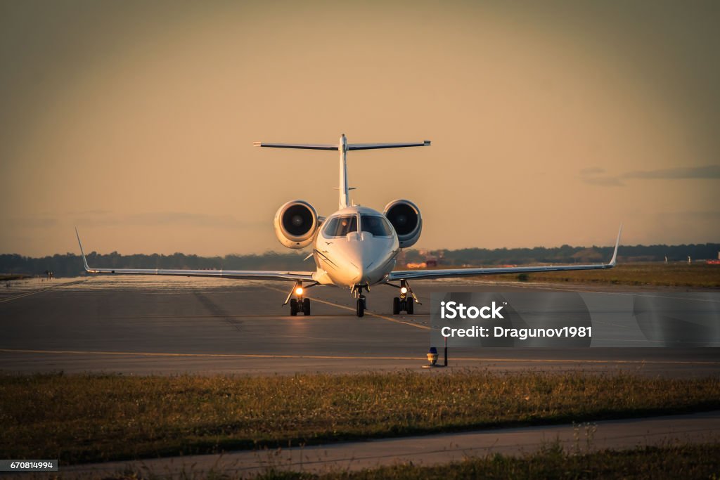 Business jet taxiing along the runway Business jet taxiing along the runway in the airport on sunset Corporate Jet Stock Photo