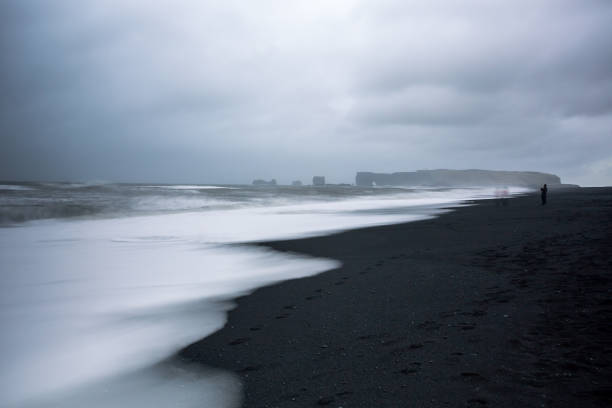 Reynisfjara black sand beach is located in southern Iceland, nearby a village called Vik. The beach is ranked as one of the most beautiful non-tropical beaches. Seen from the distance, is the small peninsula Dyrholaey.