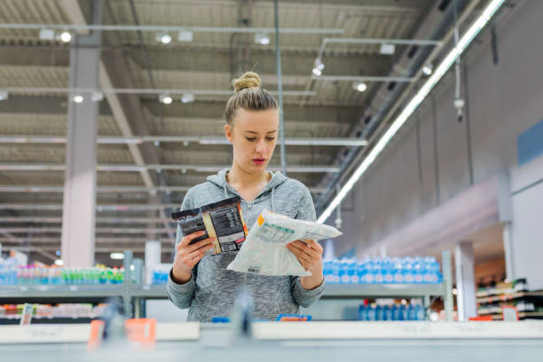 Only the freshest produce for my fridge! Pregnant Woman buying frozen food and holding a deep-frozen product in a supermarket, I always check the ingredients. Cheerful young female holding food from refrigerator while standing in a food store convenience food stock pictures, royalty-free photos & images