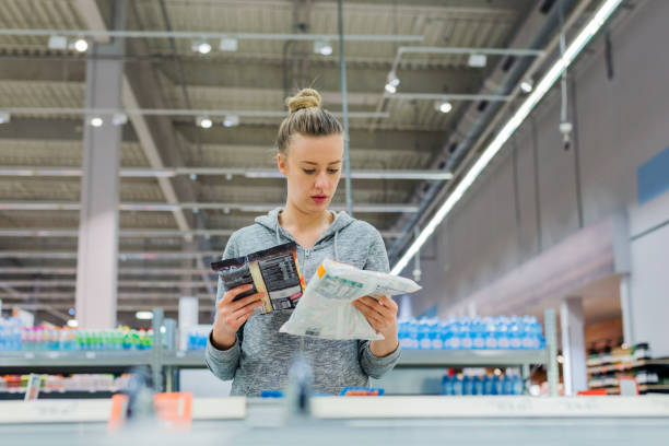 Only the freshest produce for my fridge! Pregnant Woman buying frozen food and holding a deep-frozen product in a supermarket, I always check the ingredients. Cheerful young female holding food from refrigerator while standing in a food store ready to eat stock pictures, royalty-free photos & images