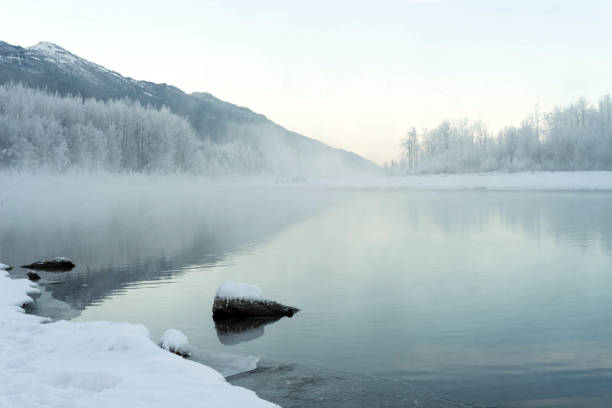 Mist rises off a river in snow covered scenery in Alaska during winter