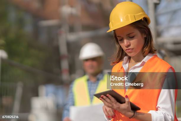 Pensive Thoughtful Young Civil Engineer Working With Her Touchless Tablet On Construction Site Stock Photo - Download Image Now