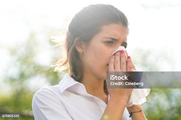Sick Woman Blowing His Nose Into Tissue Outdoors Stock Photo - Download Image Now - Allergy, Pollen, Springtime