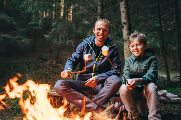 istock Father and son roast marshmallow candies on the campfire in forest 670835210