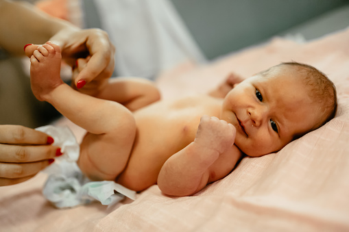 Parent changing beautiful newborn's diapers