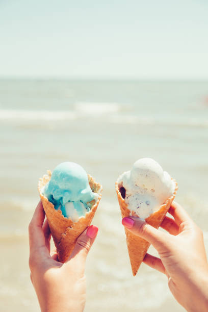 istock Woman's hands is holding two ice cream on sea background. Summer. Vacation. 670835706