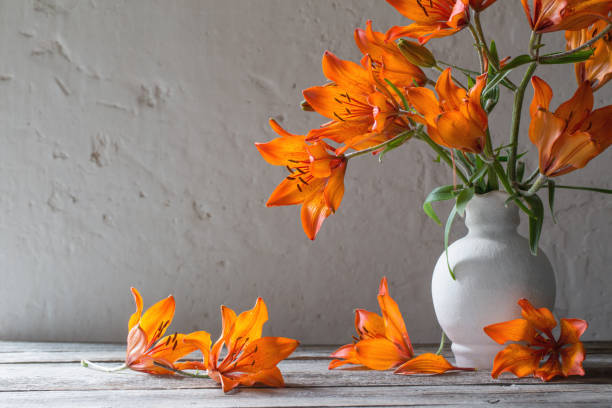 istock orange lily in vase on wooden table 670839770