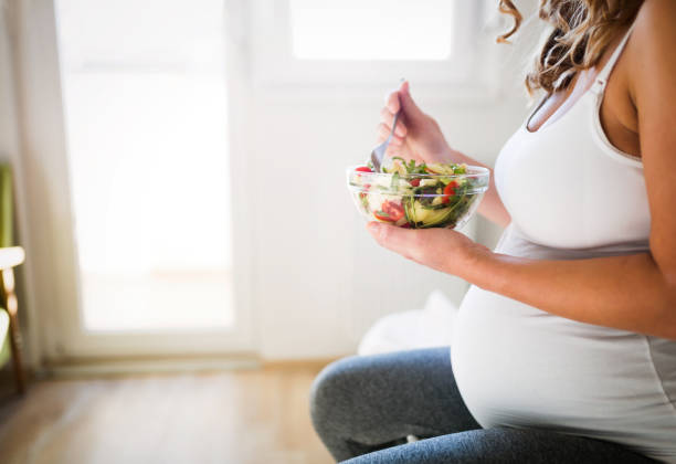 Beautiful pregnant woman eating healthy food and salads Beautiful pregnant woman eating healthy food and salads serbia and montenegro stock pictures, royalty-free photos & images