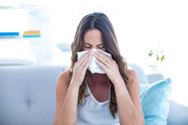 istock Sick woman sneezing on sofa 670852620