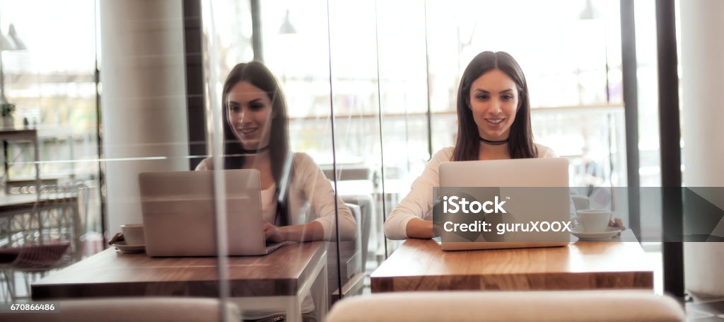 Smiling young woman drinking a coffee and surfing on internet Portrait of smiling young woman drinking a coffee and surfing on internet on her laptop computer Adult Stock Photo