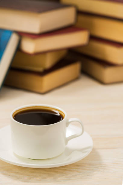 istock White cup of coffee on a table next to the books. 670869816