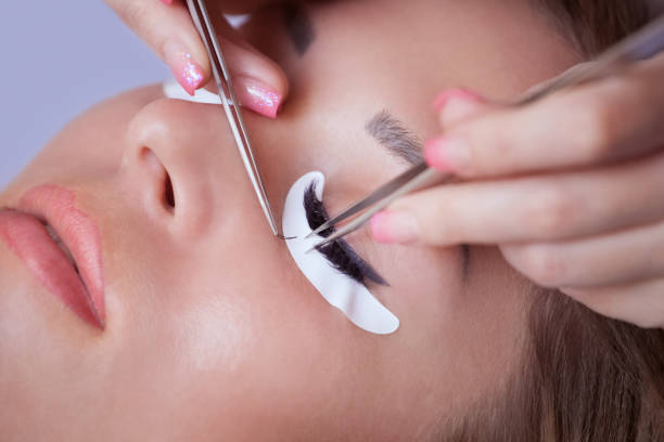 istock Makeup Master corrects, and strengthens eyelashes beams, holding out a pair of tweezers 670880372