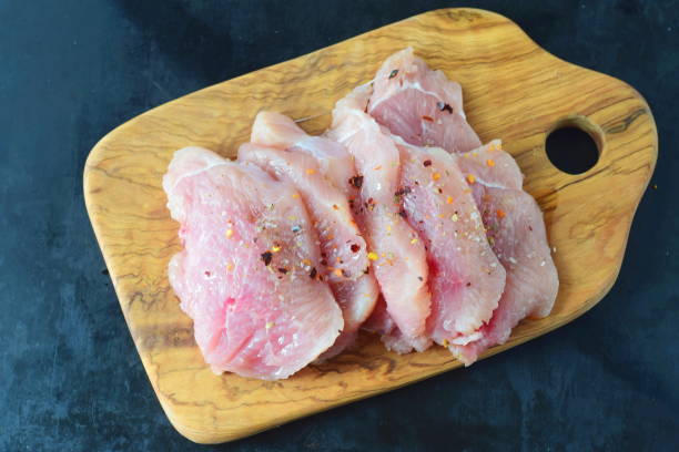 istock Raw chicken breast sliced and spiced on a olive wood cutting board 670884292
