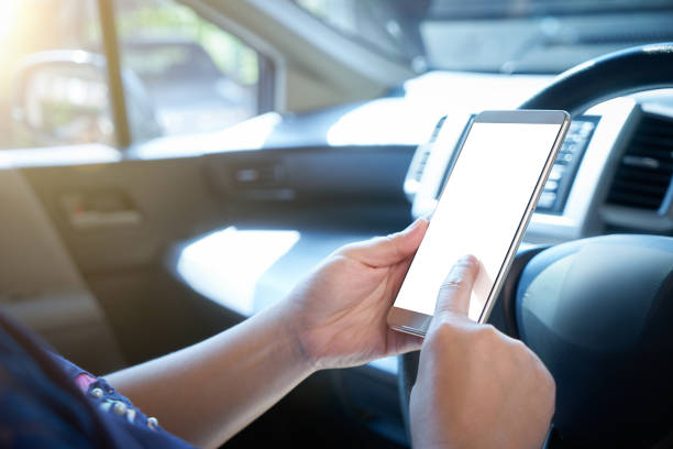 istock Woman driver using smart phone in car during traffic jam , blank white screen for design purpose . 670887166