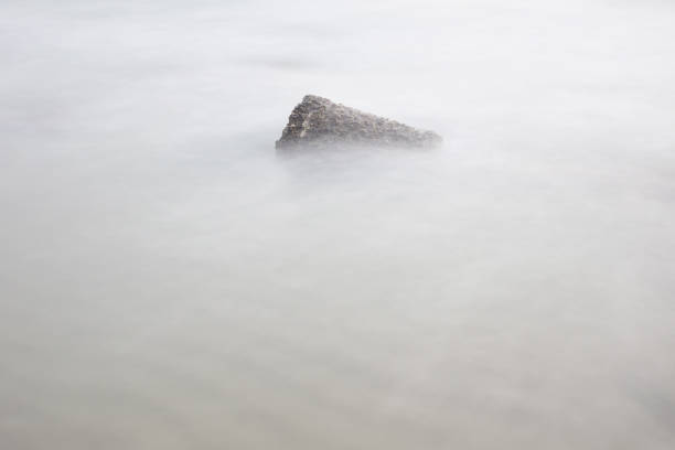 The rocky coastline in Allinge on Bornholm on a very foggy day in aprile. You can barely see the horizon - but seaulls are resting on the rocks of granite.