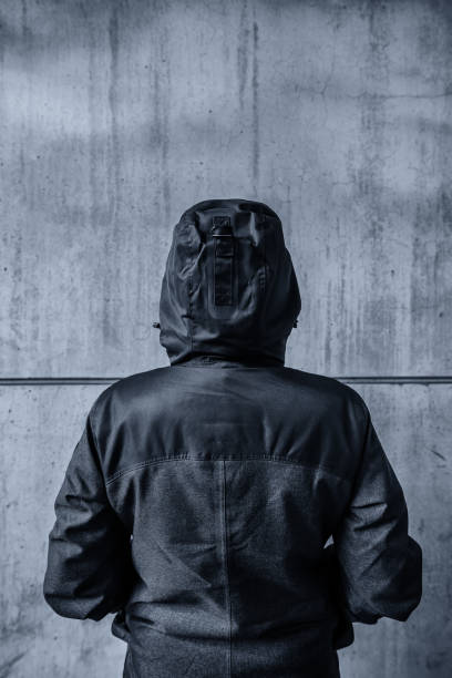 istock Unrecognizable hooded female person facing concrete wall 670897432