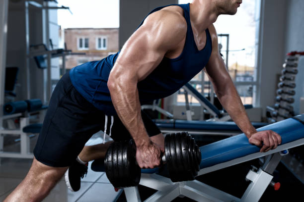 istock Man doing exercises with one dumbbell in the gym close-up 670898318