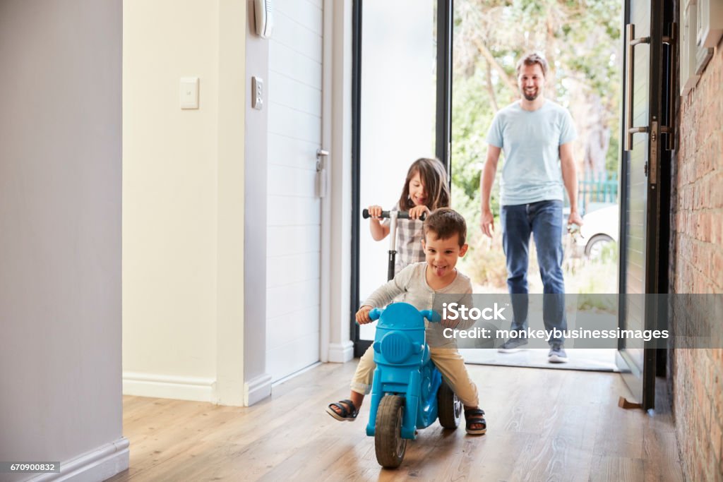 Excited Children Arriving Home With Father Family Stock Photo