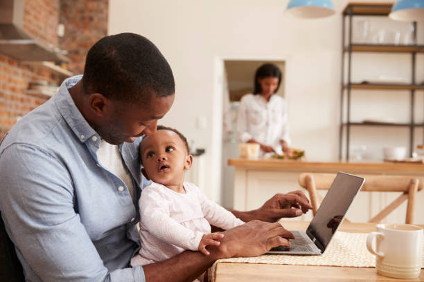 Father And Baby Daughter Use Laptop As Mother Prepares Meal Father And Baby Daughter Use Laptop As Mother Prepares Meal 3 6 months stock pictures, royalty-free photos & images