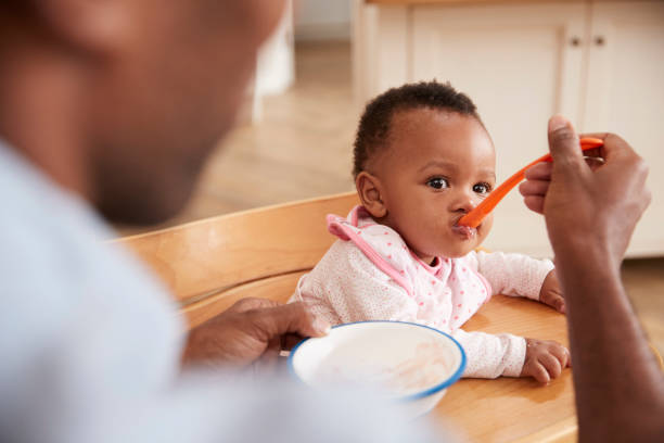 le père alimentation bébé fille en chaise haute - baby food photos et images de collection