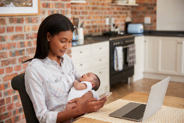 istock Mother Working On Laptop Holds Newborn Son And Sends Text 670901006