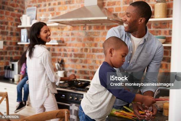 Niños Ayudando A Los Padres Para Preparar Comida En La Cocina Foto de stock y más banco de imágenes de Familia