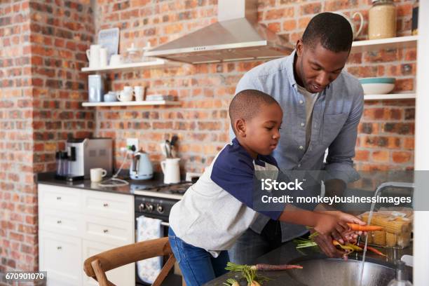 Photo libre de droit de Fils Père Daider Pour Préparer Des Légumes Pour Repas Dans La Cuisine banque d'images et plus d'images libres de droit de Cuisiner