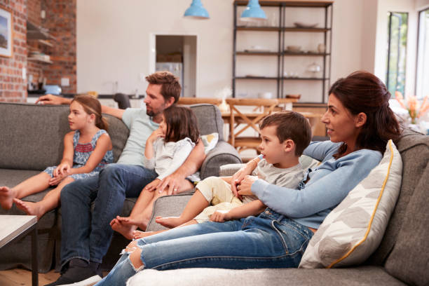 istock Family Sit On Sofa In Open Plan Lounge Watching Television 670901190