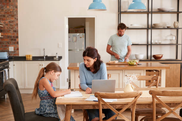 mutter hilft tochter bei den hausaufgaben als vater macht mahlzeit - two parent family indoors home interior domestic kitchen stock-fotos und bilder