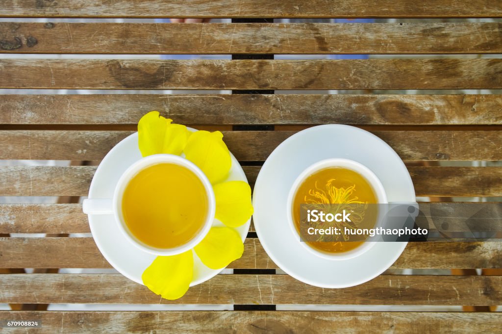 Yellow Silk Cotton flower with couple of tea cup on ceramic dishes on wooden table. Abstract Stock Photo Yellow Silk Cotton flower with couple of tea cup on ceramic dishes on wooden table. Abstract Stock Photo