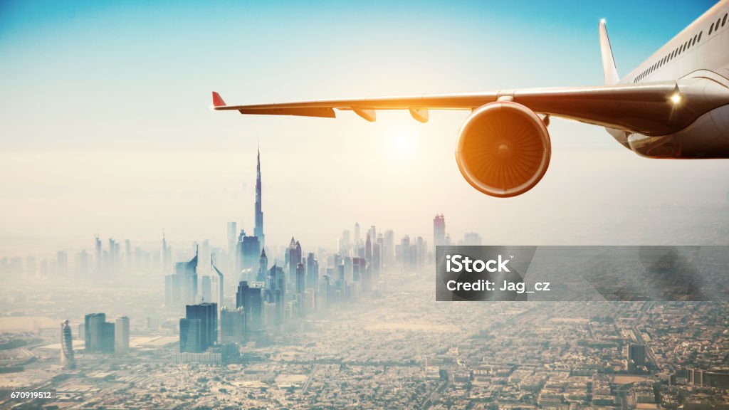 Close-up of commercial airplane flying over modern city Close-up of commercial airplane flying over modern city. Concept of fast transportation and travel. Dubai Stock Photo