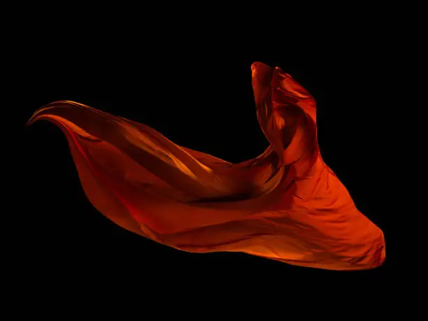 Smooth elegant red cloth separated on black background. Texture of flying fabric.