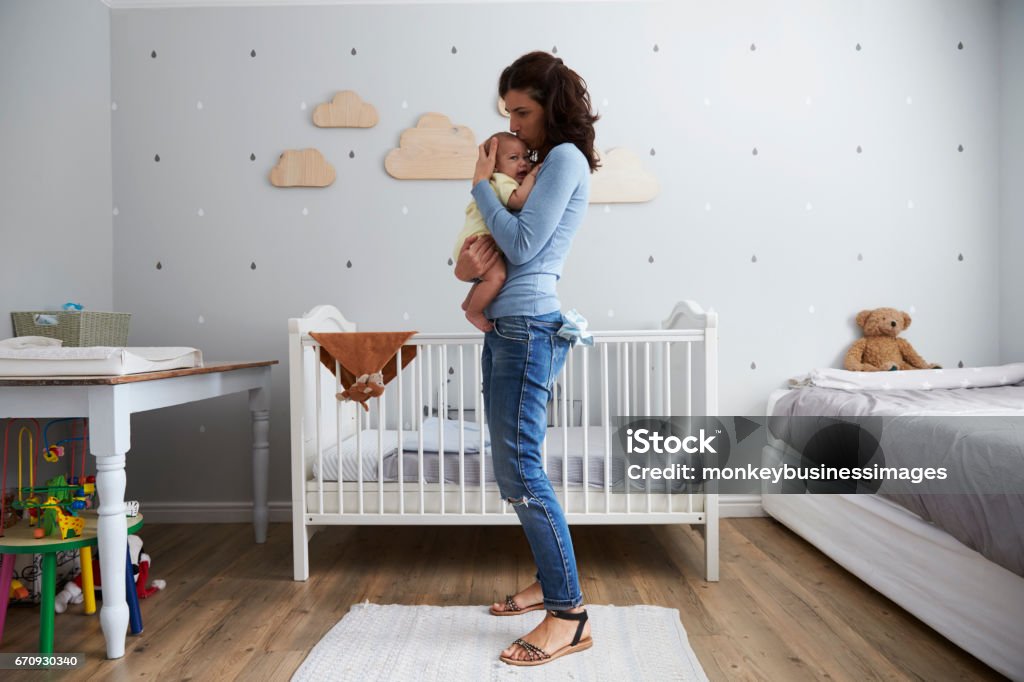 Mother Comforting Newborn Baby Son In Nursery Baby - Human Age Stock Photo
