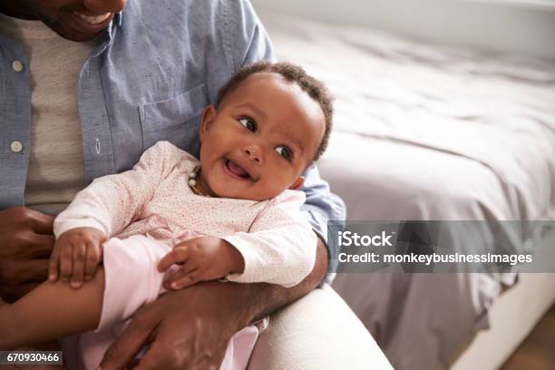 Close Up Of Father Holding Baby Daughter In Nursery Stock Photo - Download Image Now