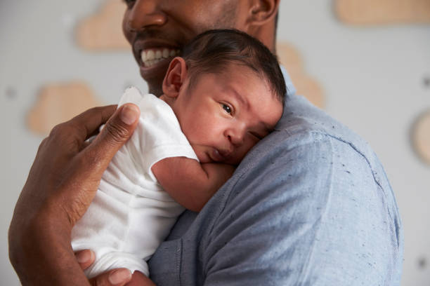 nahaufnahme von vater holding newborn baby sohn im kindergarten - genderblend stock-fotos und bilder