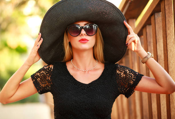 istock Glamorous young lady in big black hat in summer park 670931030