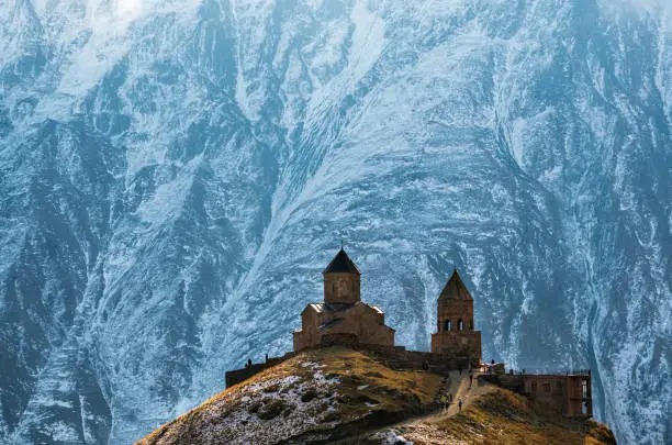 Caucasus mountains, ancient Gergeti Trinity church Tsminda Sameba against the glacier near mount Kazbek, landmark of Georgia