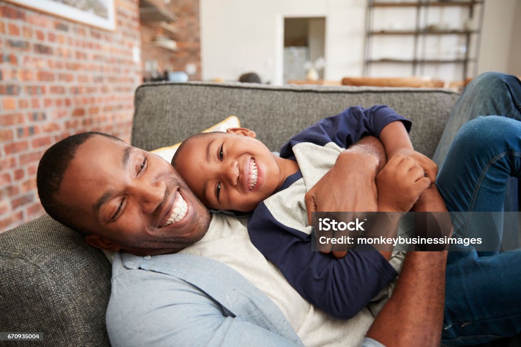 Padre e hijo abrazo juntos en el sofá - Foto de stock de Padre libre de derechos