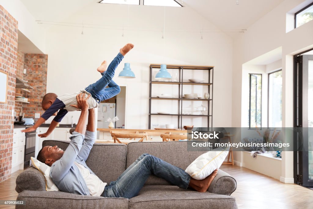 Father And Son Having Fun Playing On Sofa Together Family Stock Photo