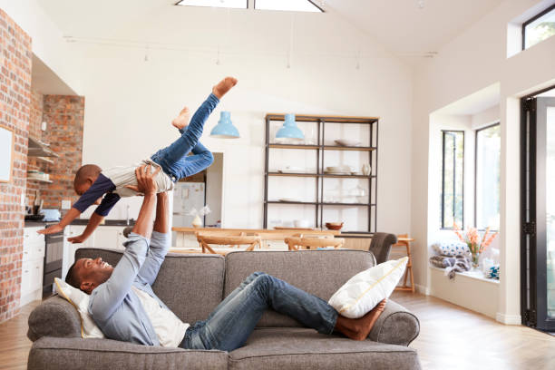 Father And Son Having Fun Playing On Sofa Together Father And Son Having Fun Playing On Sofa Together fashionable dad stock pictures, royalty-free photos & images