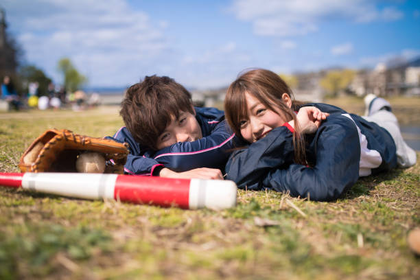 istock Young athlete couple lying on grass together after playing baseball 670941012