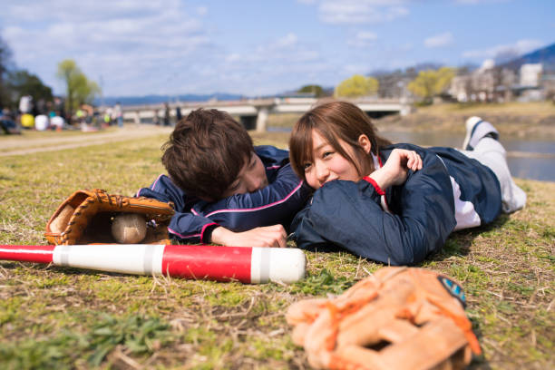 istock Young athlete couple lying on grass together after playing baseball 670941052