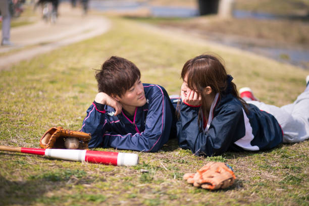 istock Young athlete couple lying on grass together after playing baseball 670941434